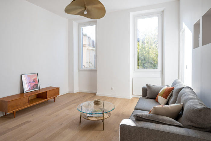 Salon avec luminaire doré et canapé gris