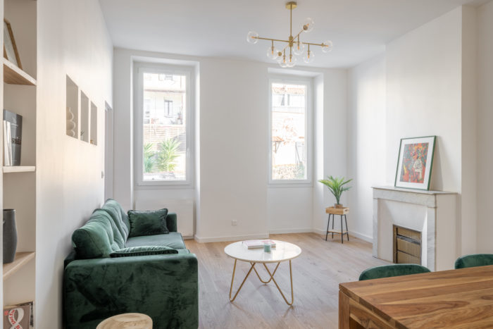 Salon avec canapé vert, table basse en marbre et cheminée en marbre blanc
