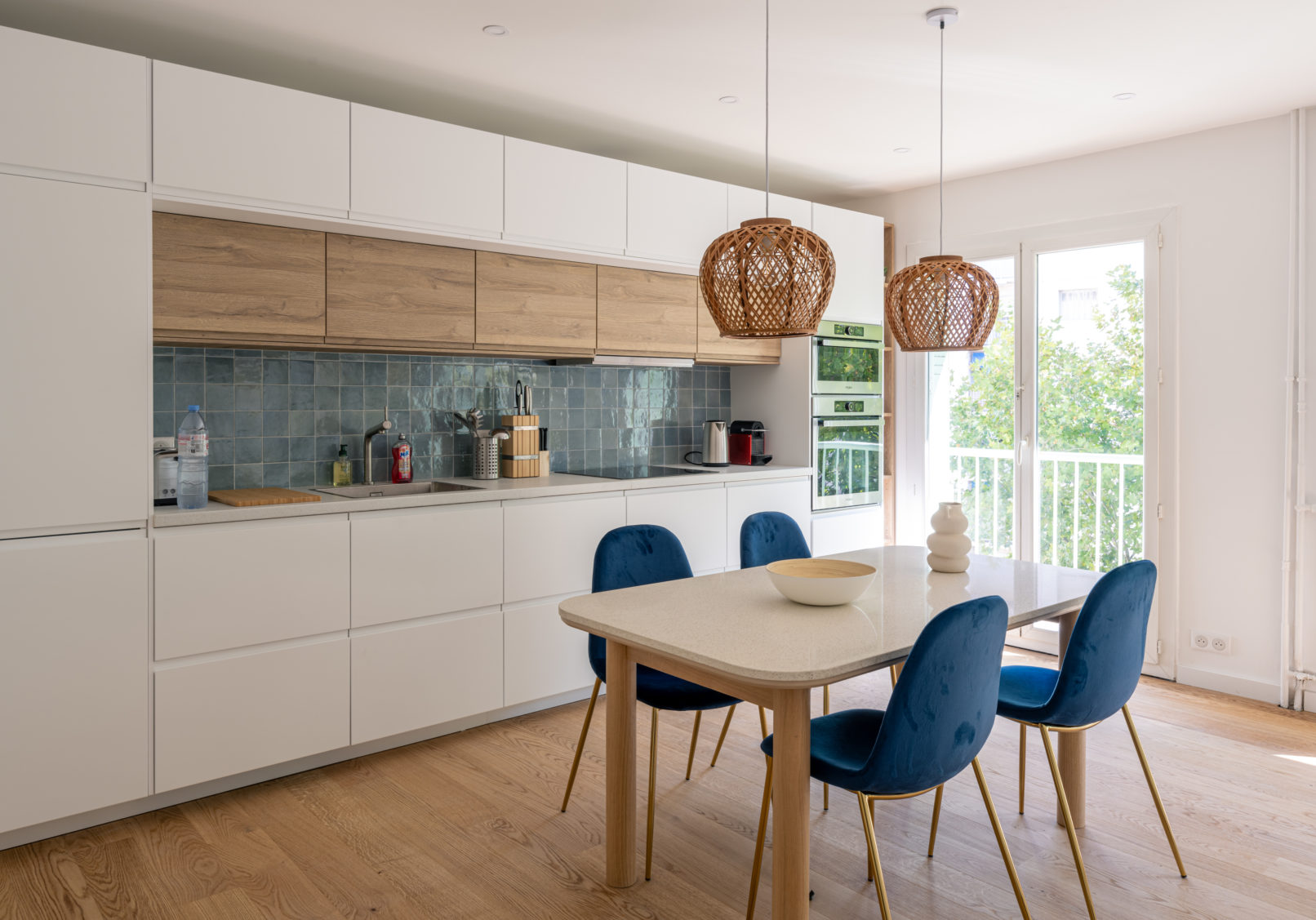Cuisine blanc et chêne, table en bois et terrazzo, chaises bleues